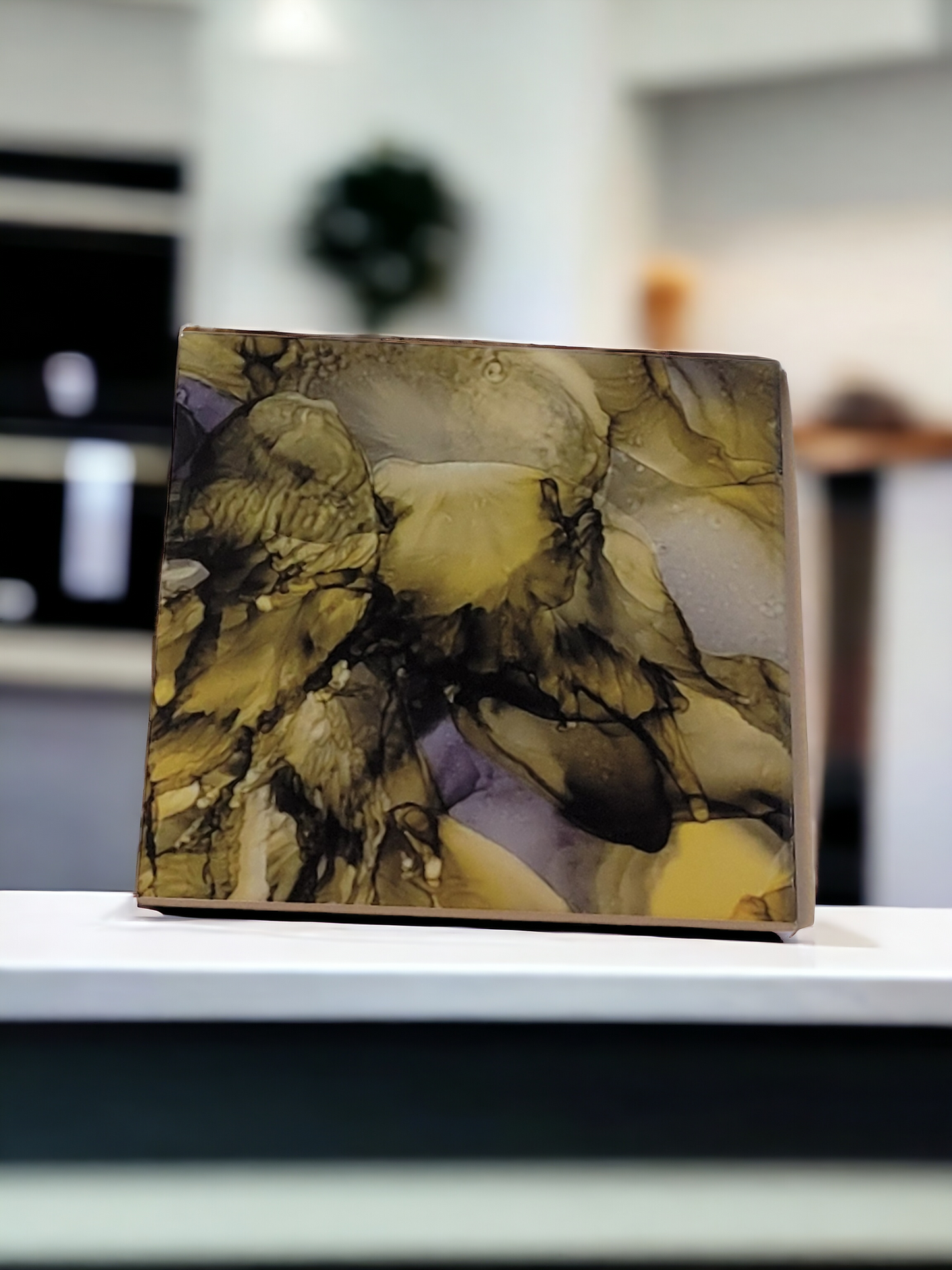 8x 8-inch ceramic tile alcohol ink art display that is an abstract design using a greenish-gold color and the sublimation process. 