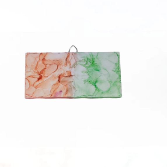 Abstract art on a 3 x 6- inch ceramic tile with a mix of orange, green, and pinkish colors. 