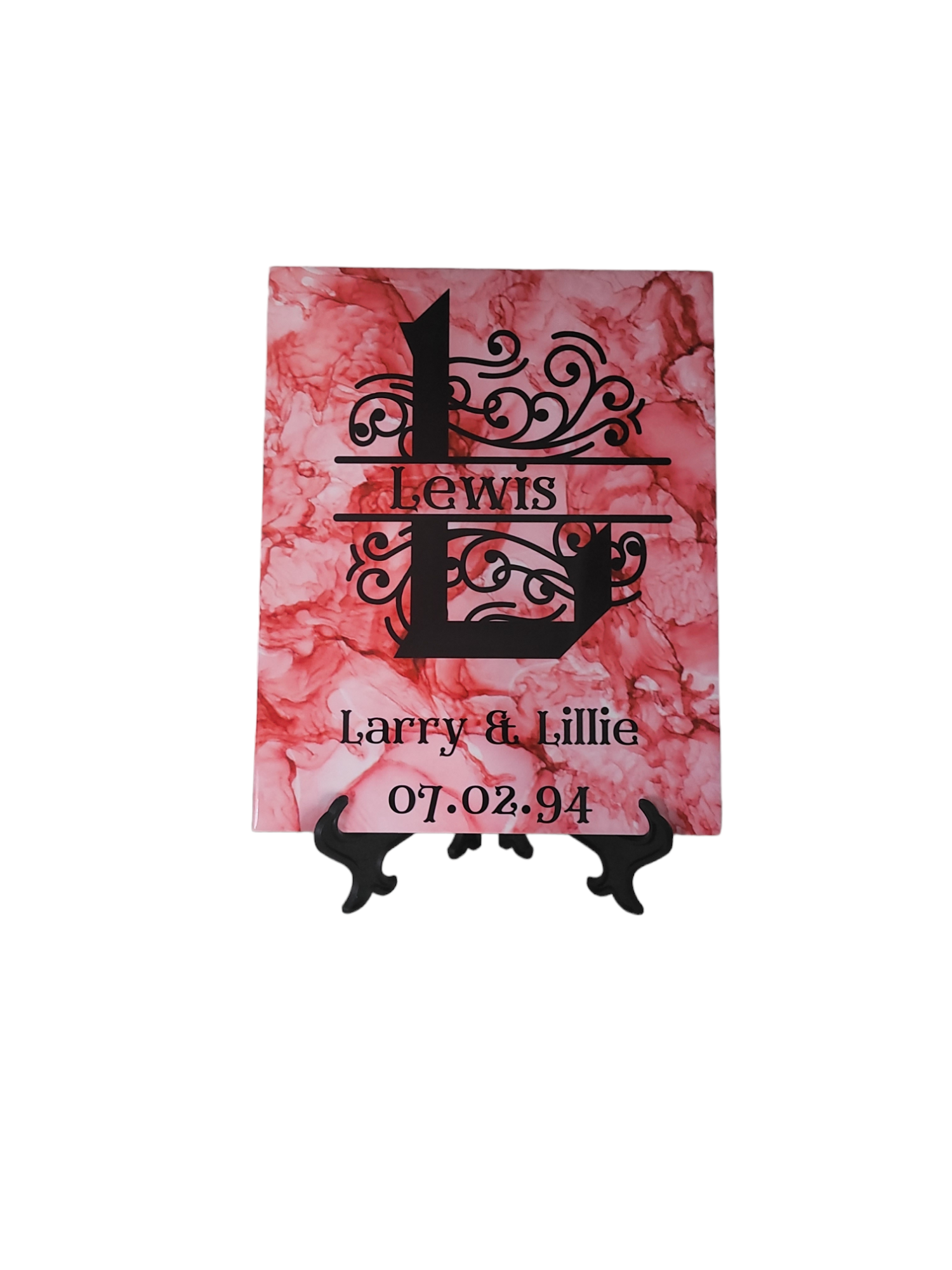 8 x 10-inch ceramic tile with a light red alcohol ink background. It features a fancy letter and space for Last name. 
At the bottom of the display is an area where the name of names go and underneath is where the wedding or anniversary date is added.