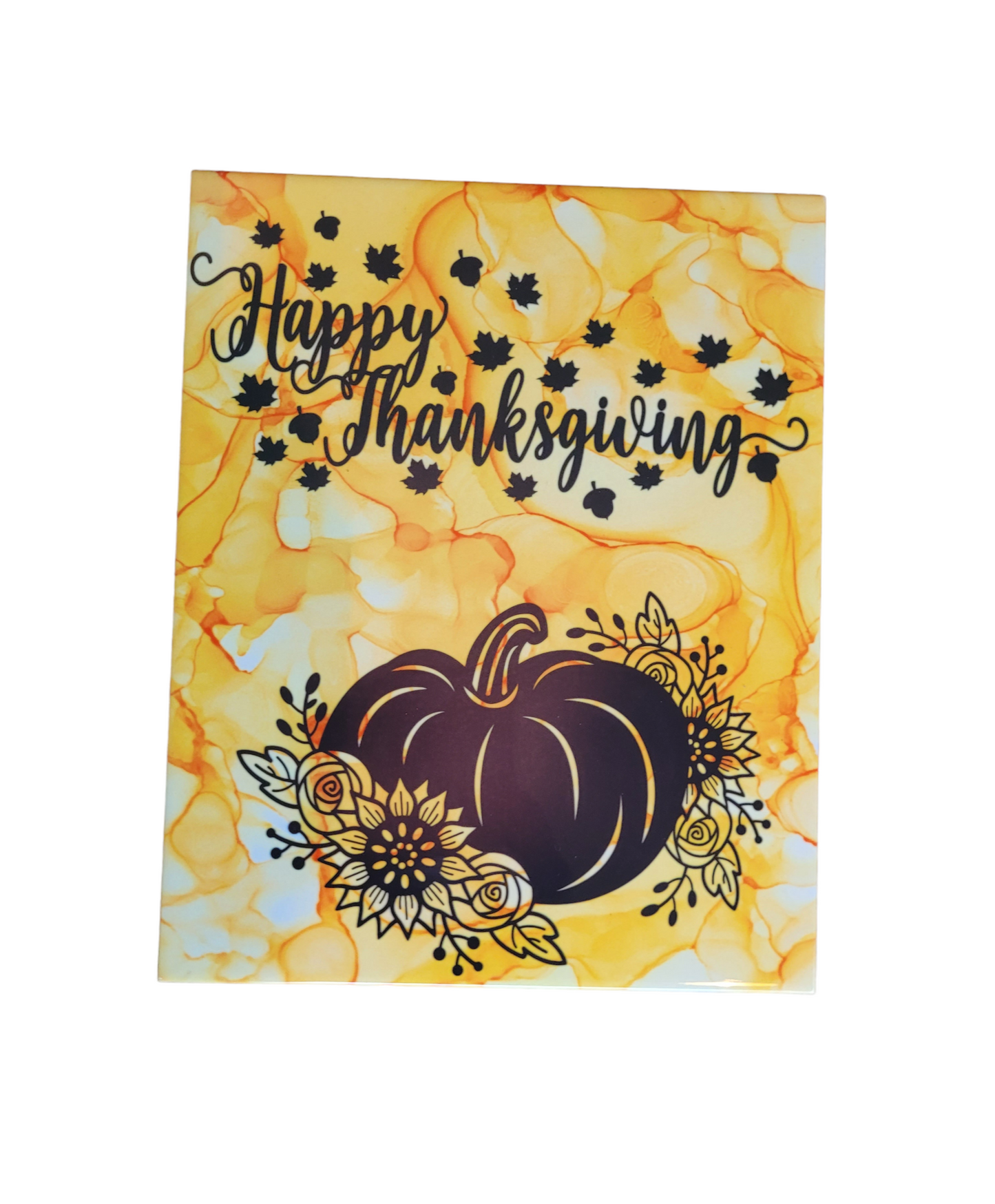 An 8 X 10-inch ceramic tile plaque with a yellowish-gold color alcohol ink background that has the words "Happy Thanksgiving" in black print with small black leaves around the words and a pumpkin at the bottom with Fall flowers