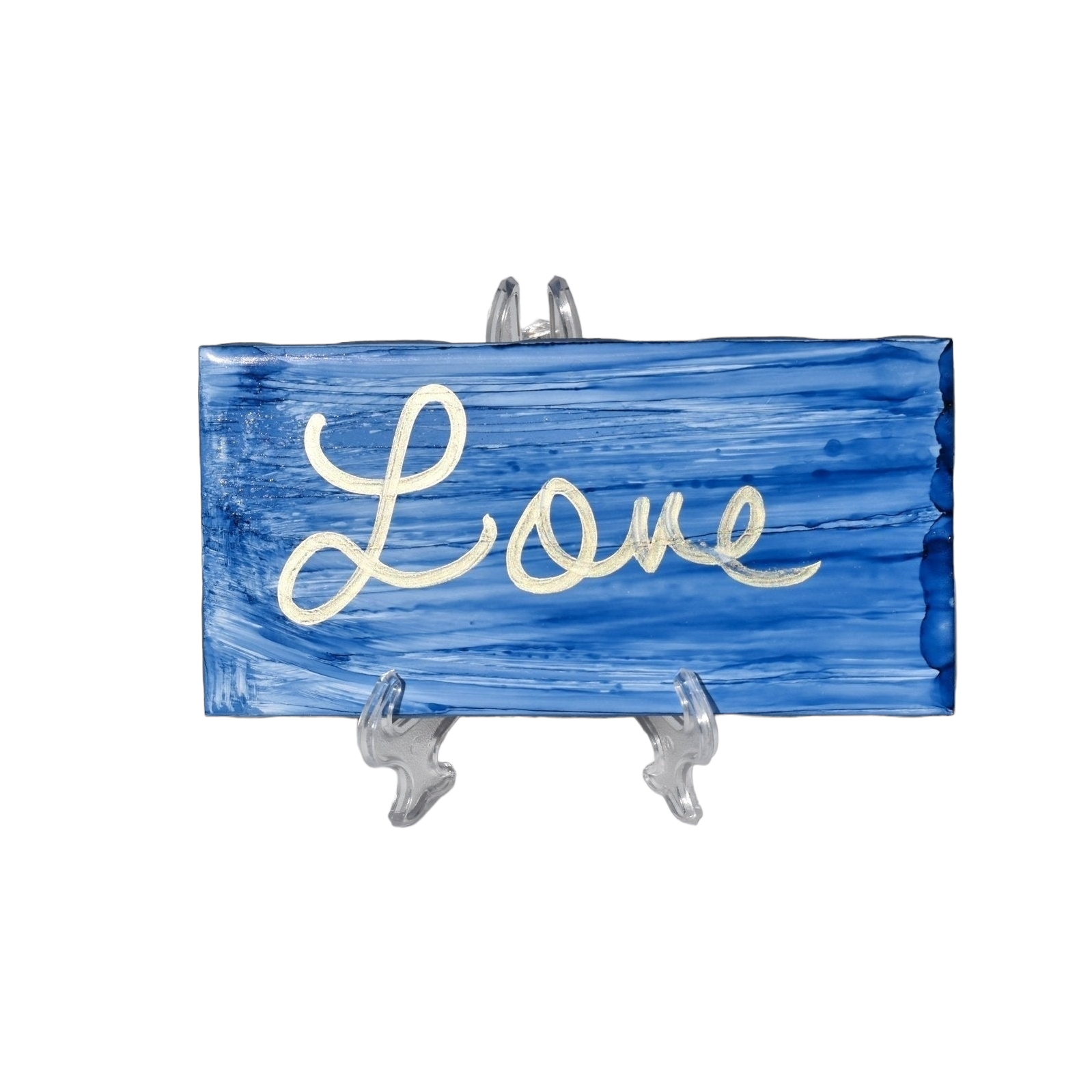 A 3X 6-inch ceramic tile with the word Love handwritten on a distressed looking background that has been painted with blue alcohol ink.