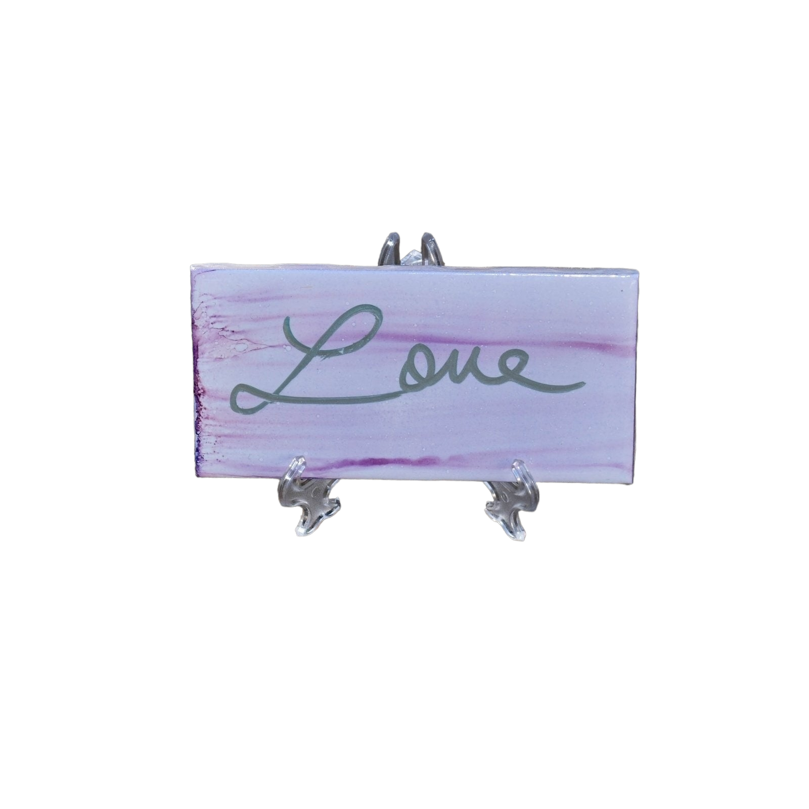 A 3X 6-inch ceramic tile with the word Love handwritten on a distressed looking background that has been painted with a very light purple colored alcohol ink.